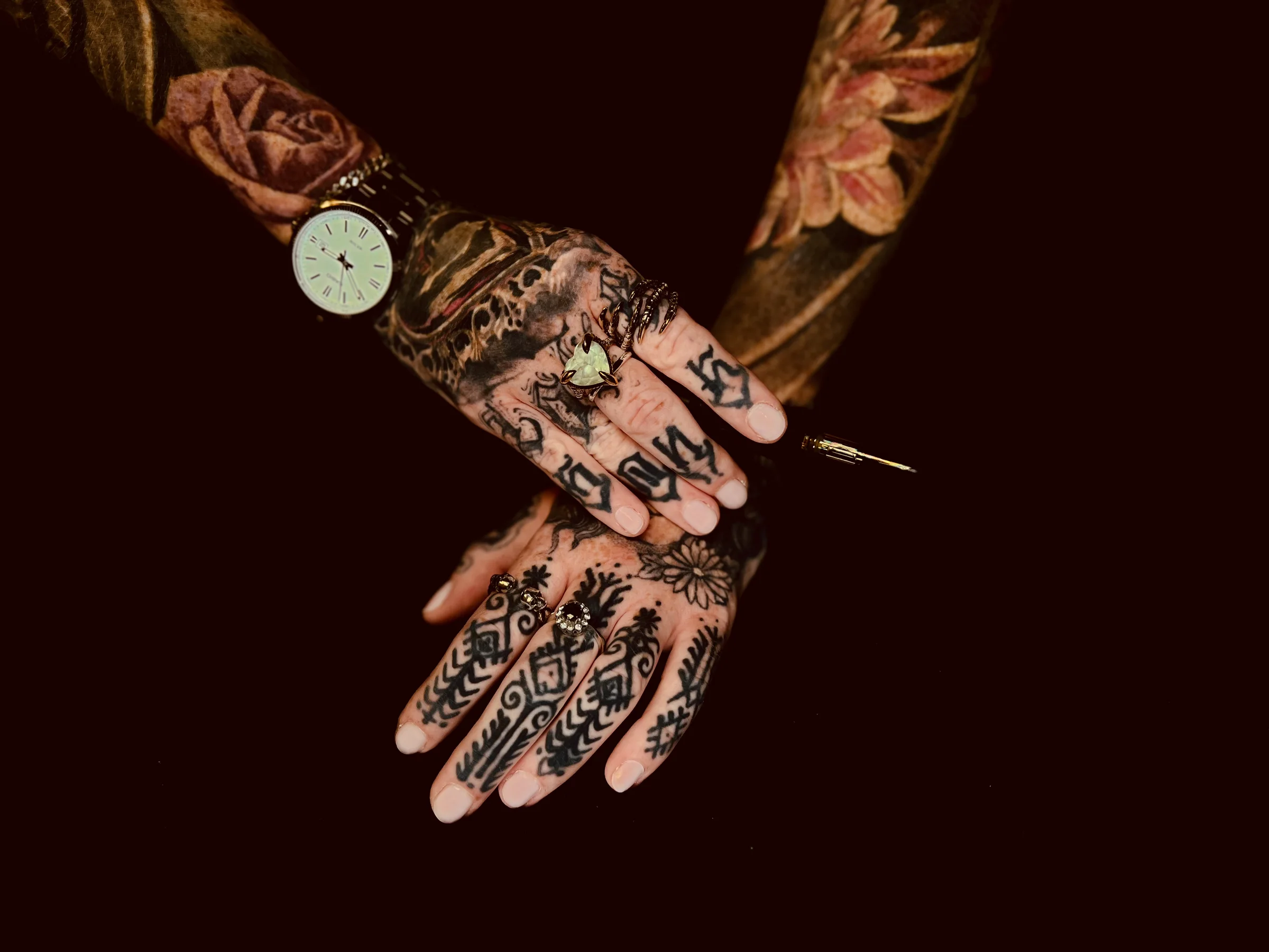 Nadine hand-poking a tattoo, ink bottle and needle resting on the arm